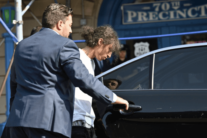 NYPD officers put 19-year-old Isiah Baez in a police vehicle during a perp walk at the 70th Police Precinct.