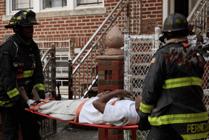Firefighters carry a man in a stretcher after the fire in East Flatbush.