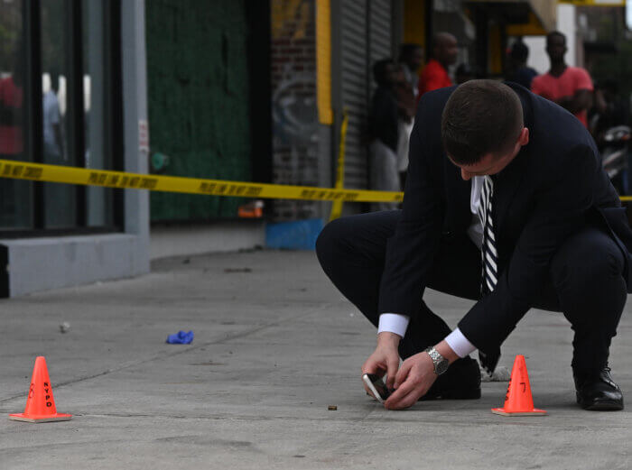 A Detective takes photos of a shell casing found near where the victim was shot