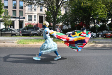 Child walks with banner of Caribbean country flags brooklyn caribbean literary festival