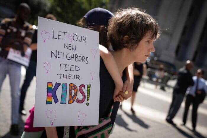 woman at migrant protest with sign