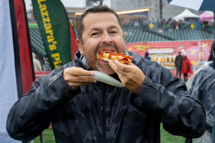 man eating pizza off plate at one bite pizza festival 