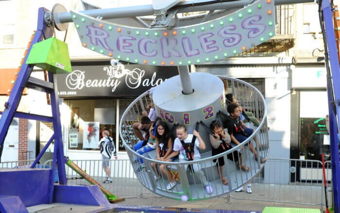 Kids cheese and grin as they ride carnival rides.