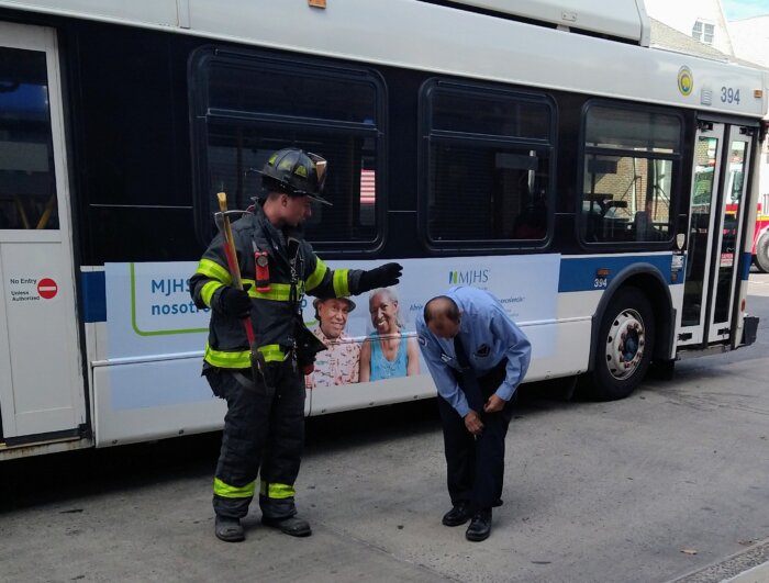 The bus driver points out his knee injury to a FDNY firefighter.