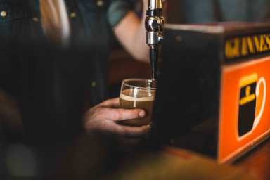 Person pulling pint of Guinness