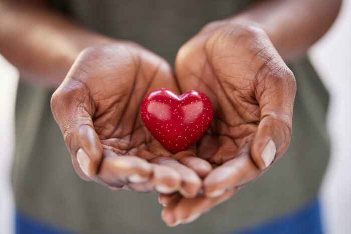 Close up of african woman hands holding red heart in solidarity