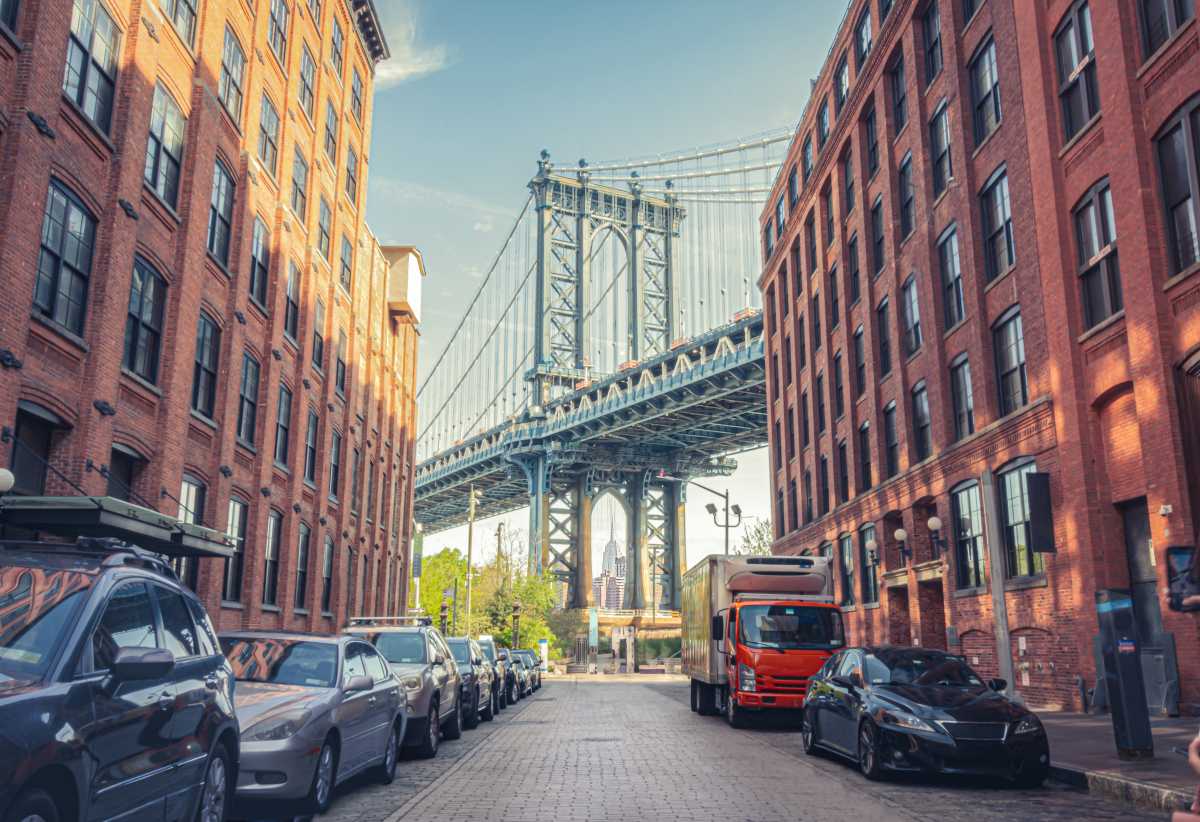 Manhattan Bridge between Manhattan and Brooklyn over East River seen from a narrow alley enclosed by two brick buildings on a sunny day in Washington street in Dumbo, Brooklyn, NYC