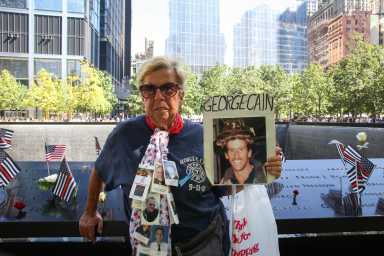 Freyda Markow pictured at the at National 9/11 Memorial and Museum holding photos of victims in the attack, including her cousin Firefighter George Cain