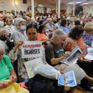 people holding signs against arrow linen rezoning