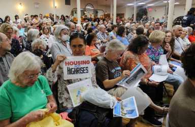 people holding signs against arrow linen rezoning