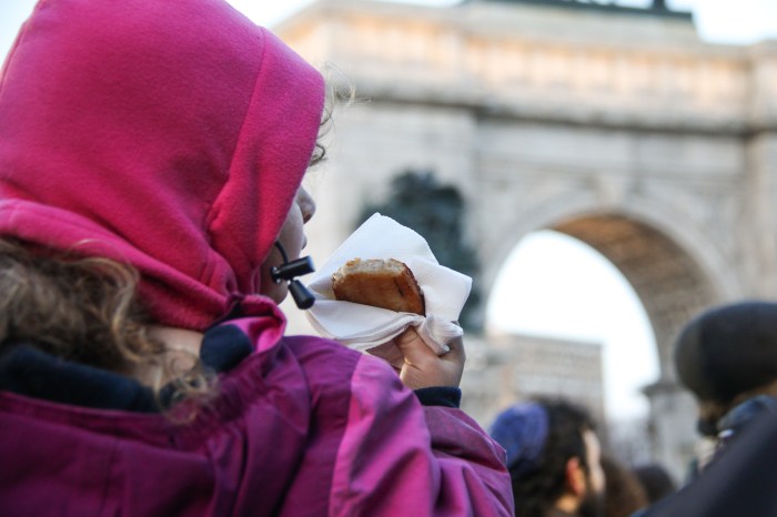 young girl eating latke at menorah lighting