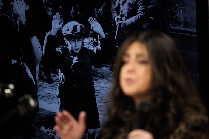 woman speaking with photo of child in camp in the background
