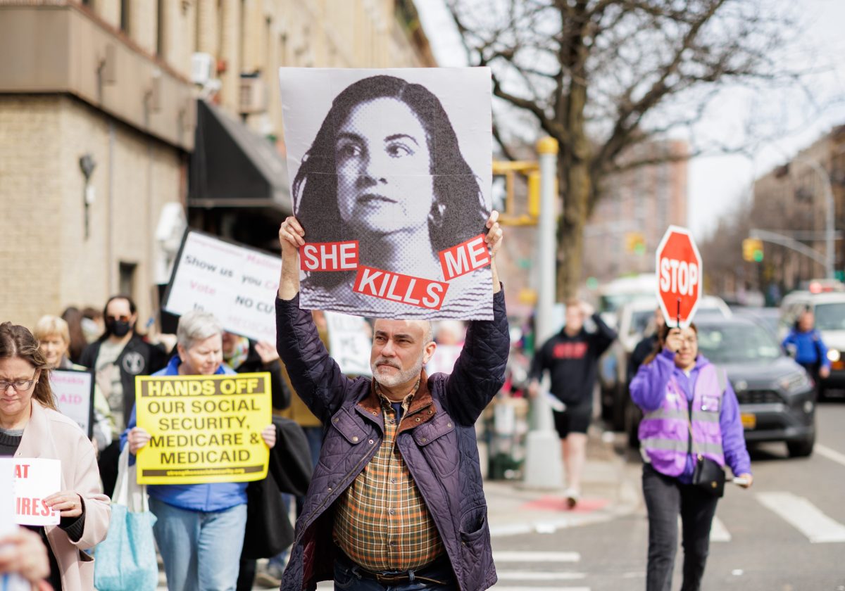 person marching with sign of malliotakis healthcare cuts