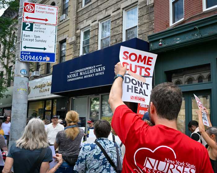 person holding sign outside malliotakis' office