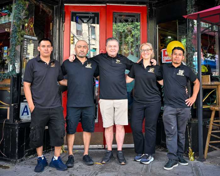 skinflints staff, dressed in black workwear, standing outside the restaurant arm-in-arm