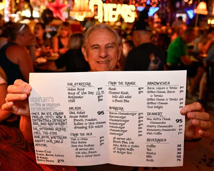 man holding up skinflints 1975 menu