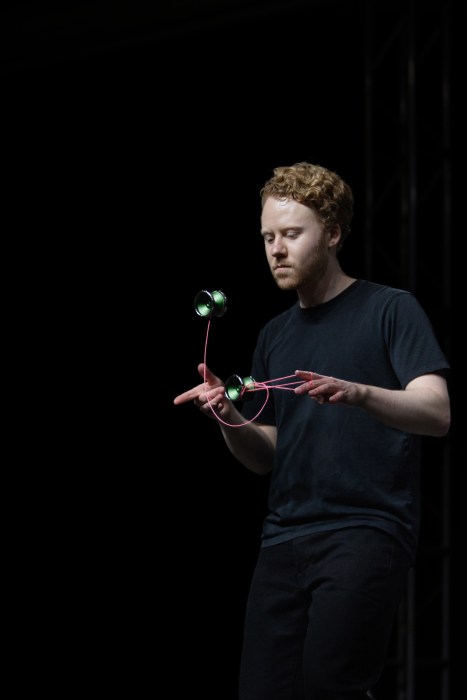 man in black shirt performs a routine with two yo-yos.