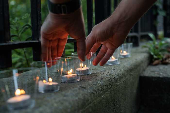 person putting down candles at morgan avenue vigil