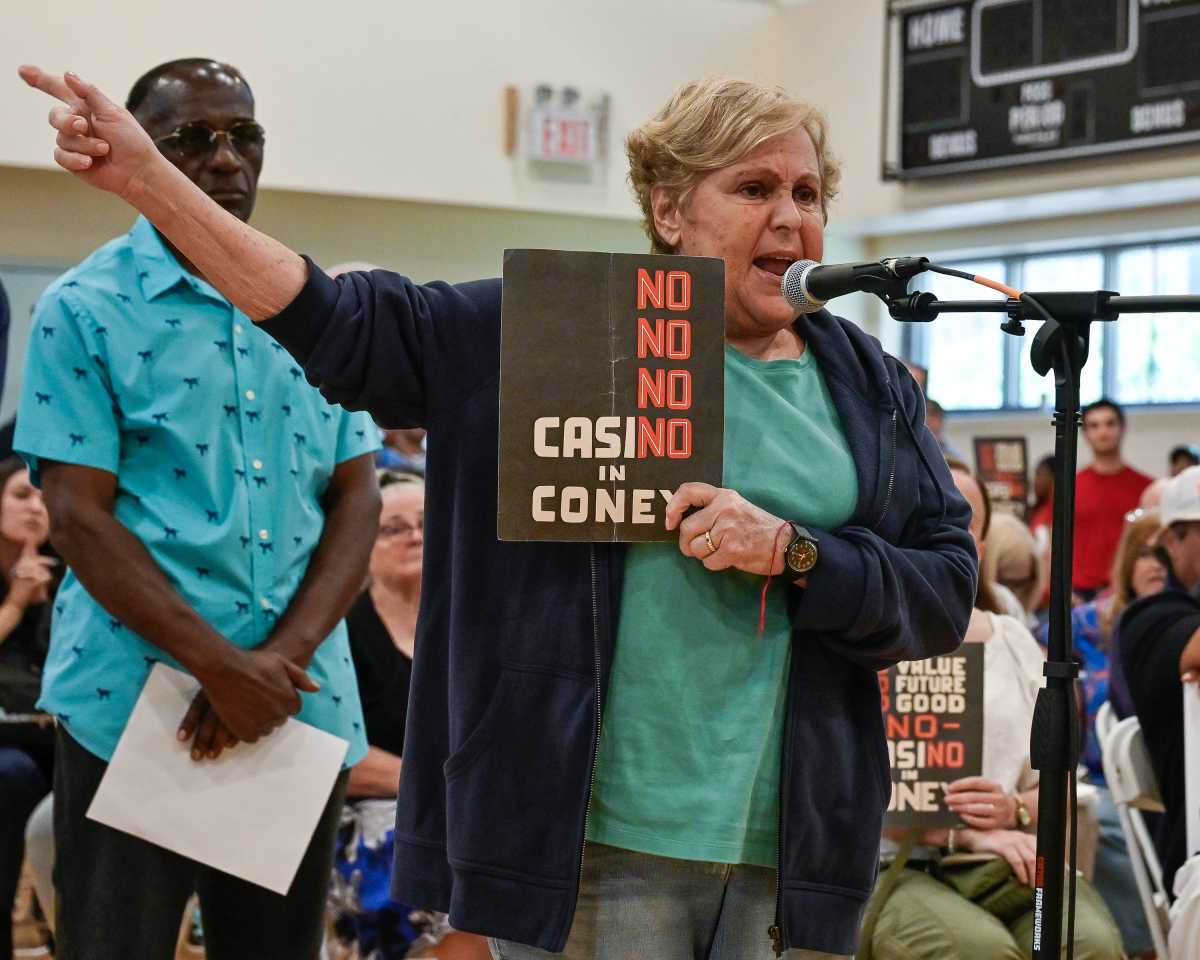 woman holding no coney island casino sign at microphone during hearing