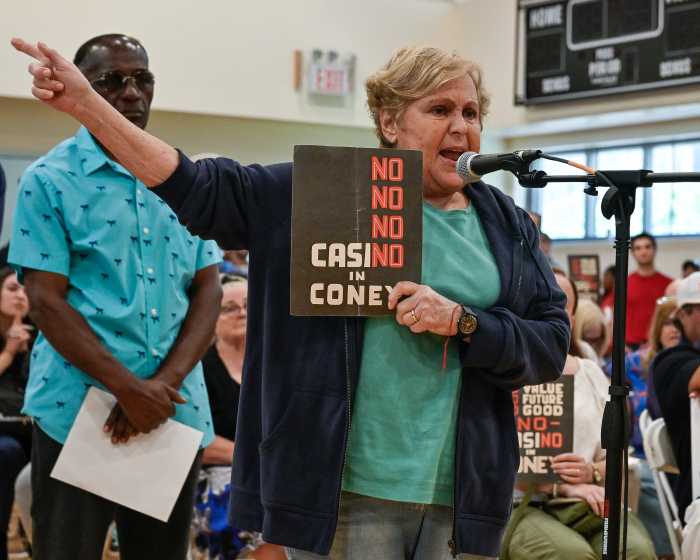 woman holding no coney island casino sign at microphone during hearing