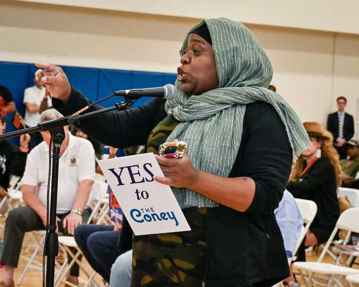woman speaking holding yes to the coney sign