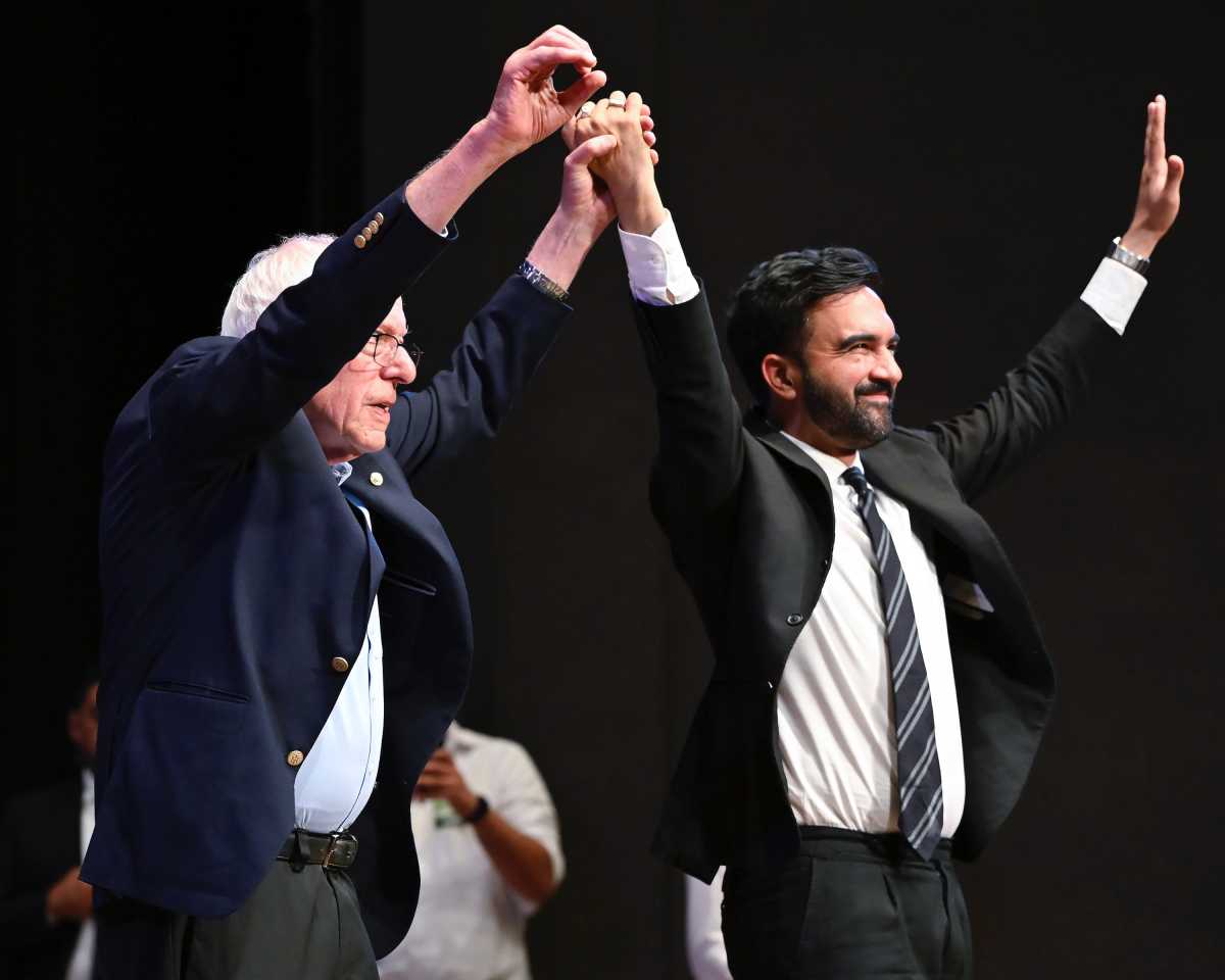Zohran Mamdani and Bernie Sanders holding hands at town hall event